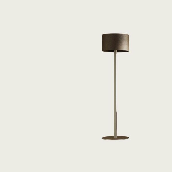 La Lámpara de pie Rems es elegante y minimalista, presenta una elegante pantalla cilíndrica sobre un soporte delgado que proporciona una iluminación suave contra un fondo sencillo y de color claro.