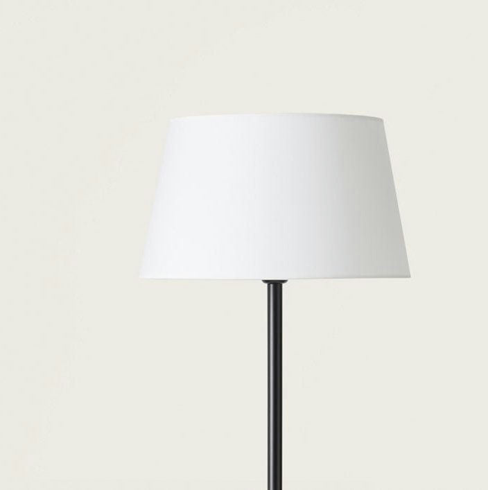 La Lámpara de pie Tex, con una pantalla blanca sobre un fondo pálido, proporciona una iluminación suave.