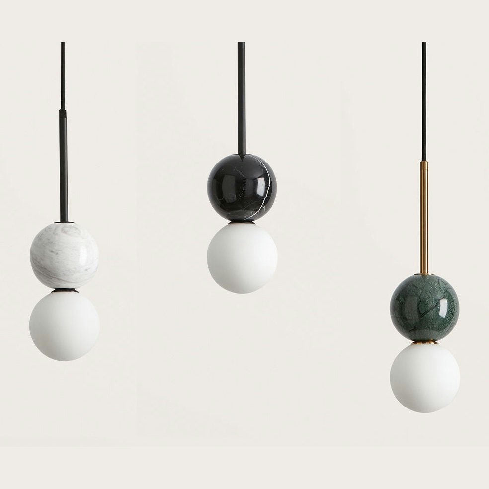 La Lámpara de techo Dalt 1 X G9 consta de tres luces colgantes con bombillas en forma de globo y un diseño minimalista. Cada luz tiene dos esferas apiladas: mármol blanco, negro y verde en la parte superior y blanco en la parte inferior. Suspendidas por cables, son ideales para una iluminación interior moderna y elegante.