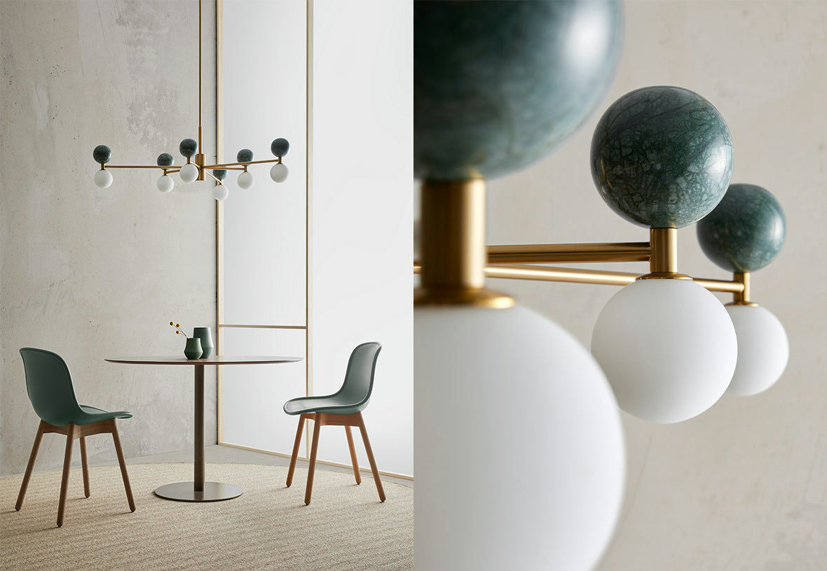 Un moderno comedor que incluye dos sillas verdes y una mesa redonda bajo la Lámpara de techo Dalt 6xG9 contemporánea con esferas de cristal y vidrio esmerilado. El diseño minimalista de la habitación, con paredes de colores claros, complementa perfectamente la lámpara de araña geométrica.