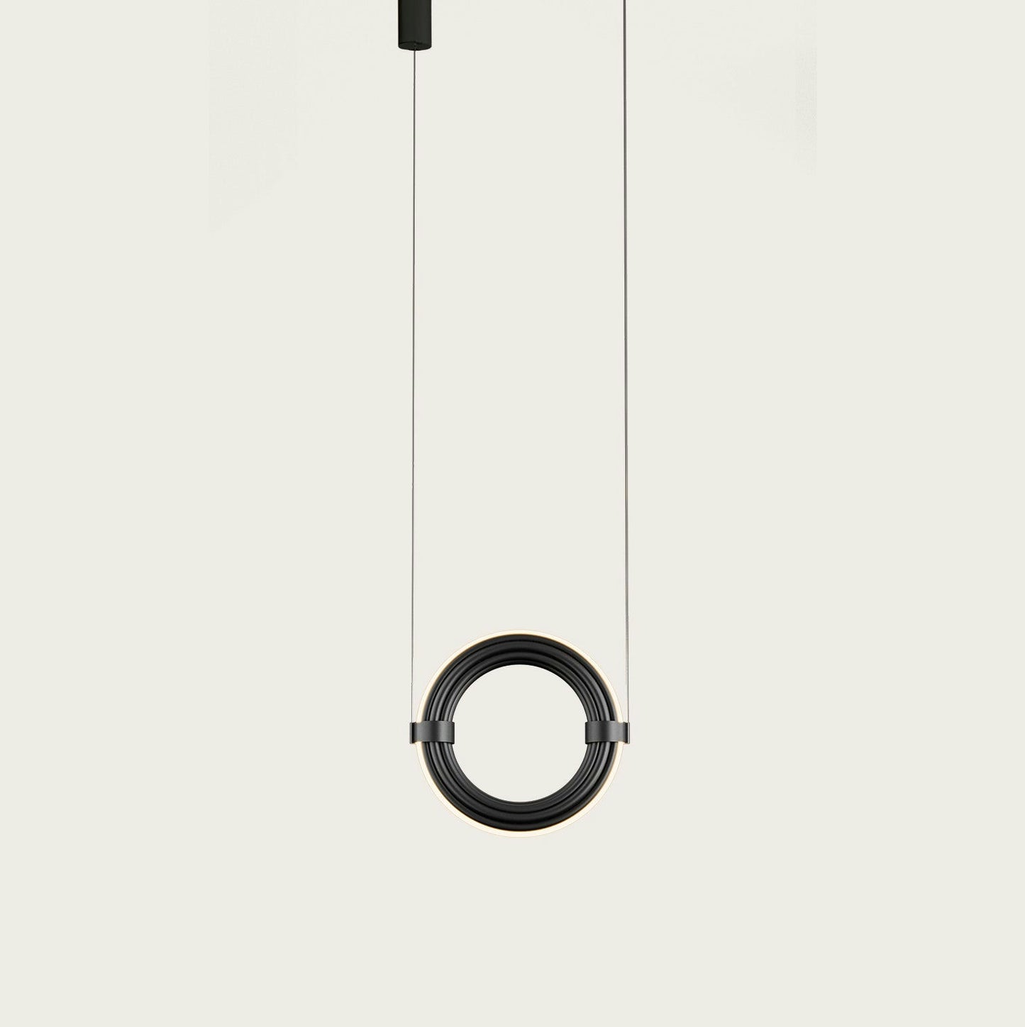 La lámpara de techo Elli (vertical) presenta un colgante circular con una elegante espiral negra, suspendida por dos cables. Esta pieza de diseño moderno ofrece una iluminación indirecta sorprendente sobre un fondo sencillo.