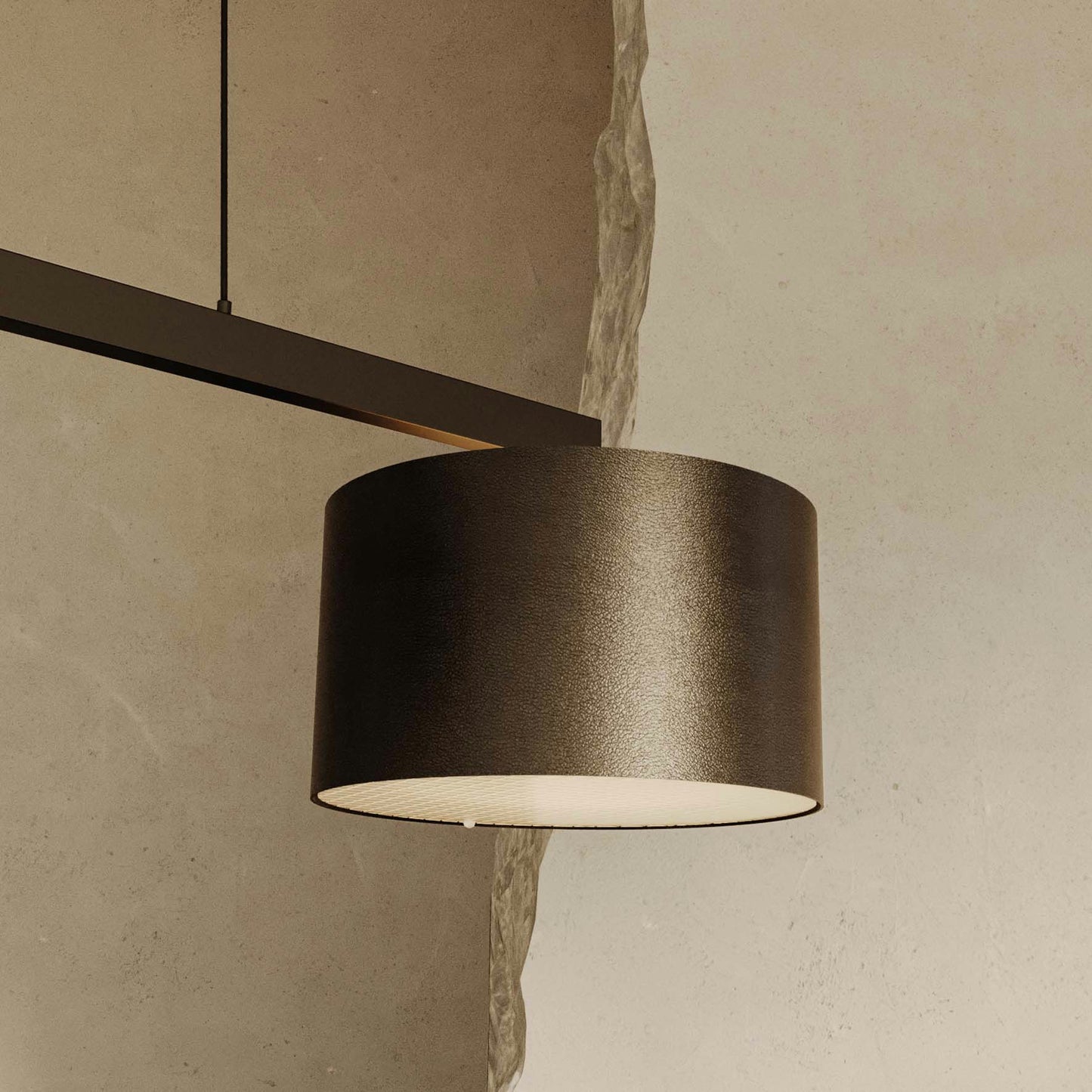 La Lámpara de techo Rems (2 luminarias), con su diseño cilíndrico minimalista negro, cuelga elegantemente de un riel de techo contra una pared beige texturizada, encarnando la elegancia contemporánea en cada detalle.