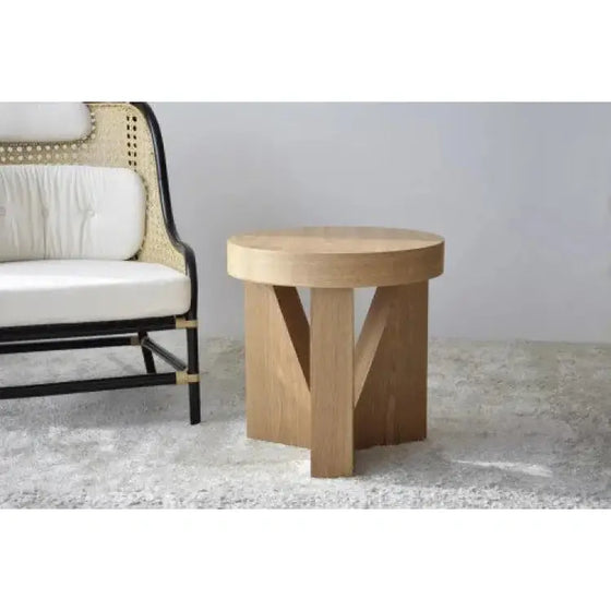 A Mesa Auxiliar Fresno Natural Mocca - Mesa auxiliar triangular junto a una silla de mimbre de diseño moderno y elegante.