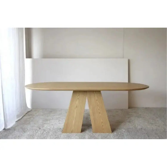 Una Mesa de Comedor Fresno Natural Elba de diseño exclusivo en una habitación blanca irradia elegancia.