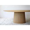 Mesa de Comedor Oval Fresno Natural - Abies: Una mesa redonda de madera en una estancia blanca, diseñada con Mesa de Comedor Oval Fresno Natural - Abies.