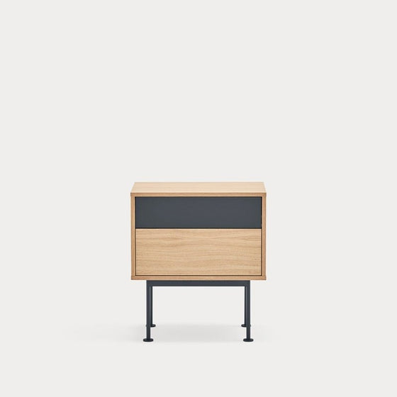 Un mueble minimalista de madera con panel negro y esbeltas patas de metal sobre un fondo liso blanco, diseñado como Mesita de noche Yoko 2C contemporánea.