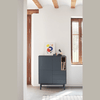 Un Mueble Auxiliar Corvo 3P3C con estantes para libros y artículos de decoración en una habitación luminosa con vigas de madera y ventana, diseñado para un almacenamiento funcional.