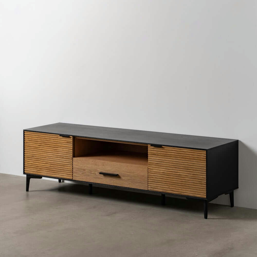 El Mueble TV Novomix Negro-Natural DM-Madera resalta la elegancia moderna con su acabado en negro y madera, dos puertas laterales y un estante central abierto. Su diseño geométrico minimalista es impresionante sobre un piso de concreto contra una pared blanca prístina.