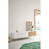 Interior de dormitorio minimalista con cómoda blanca, alfombra verde y piscina visible desde el exterior a través de la puerta abierta, con un Mueble TV Sierra 2P3C.