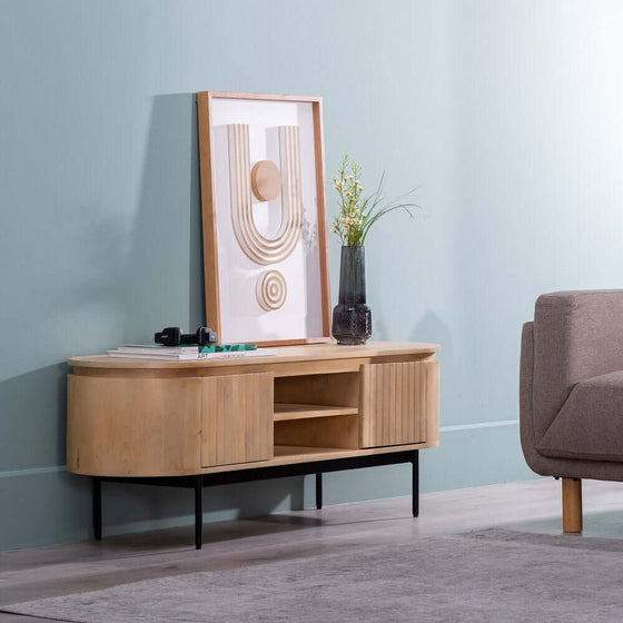 Un Mueble TV Versátil Natural-Negro en madera de mango, con elementos decorativos y un cuadro abstracto enmarcado contra una pared azul pálido al lado de un.