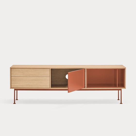 Mueble TV Yoko 1P2C moderno con dos cajones, un mueble central y puerta abierta de color naranja, sobre esbeltas patas de metal sobre un fondo liso blanco. Esta pieza ejemplifica el diseño contemporáneo con sus líneas elegantes.