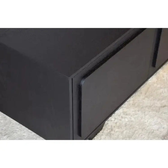 Un primer plano de un "empuje" negro que abre Mueble TV en Roble Teñido Negro - Río sobre una alfombra.