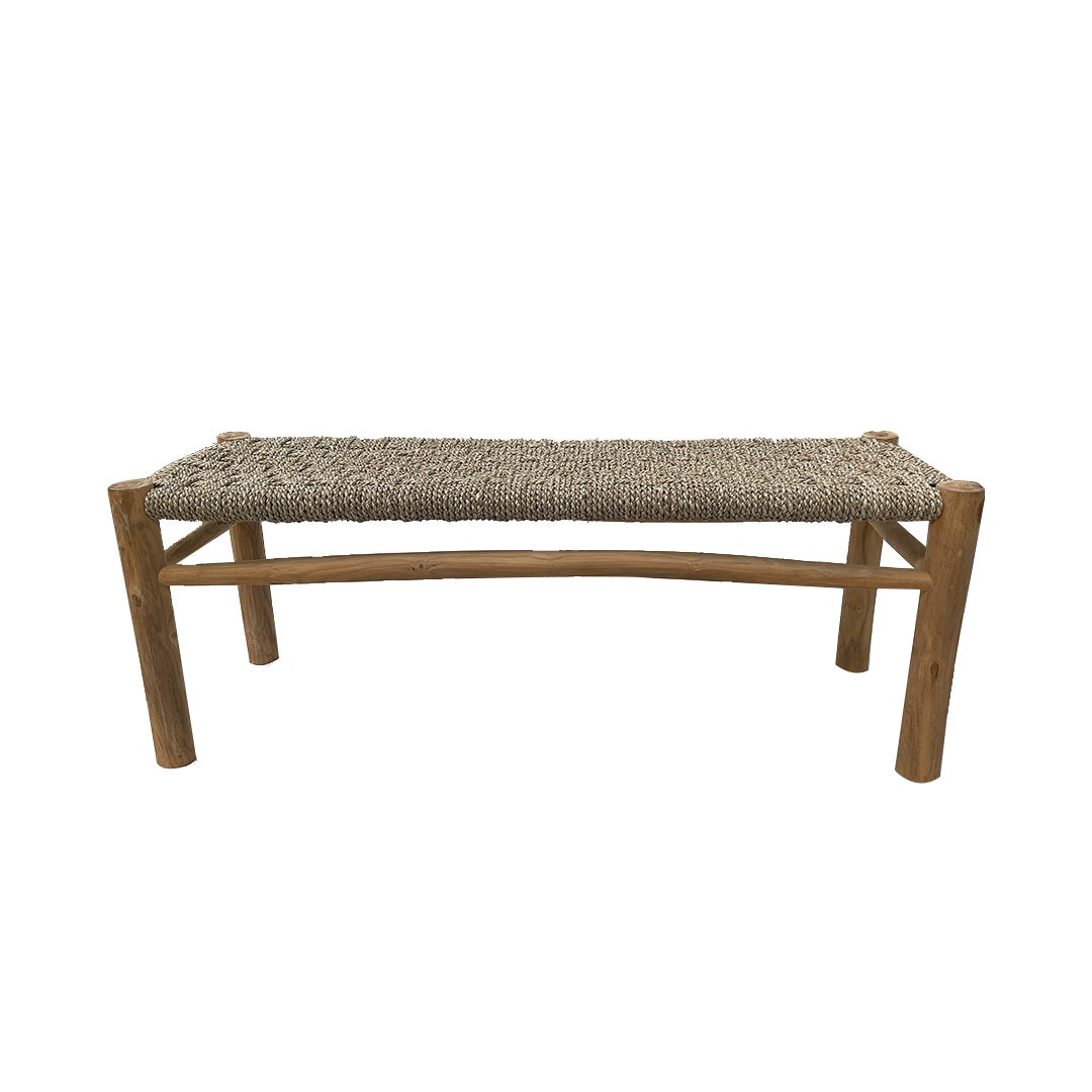 Una Banqueta de Teca y Ratán Natura de CASAPATIO, con cuatro patas y un asiento de ratán natura tejido, expuesta sobre un fondo blanco liso.