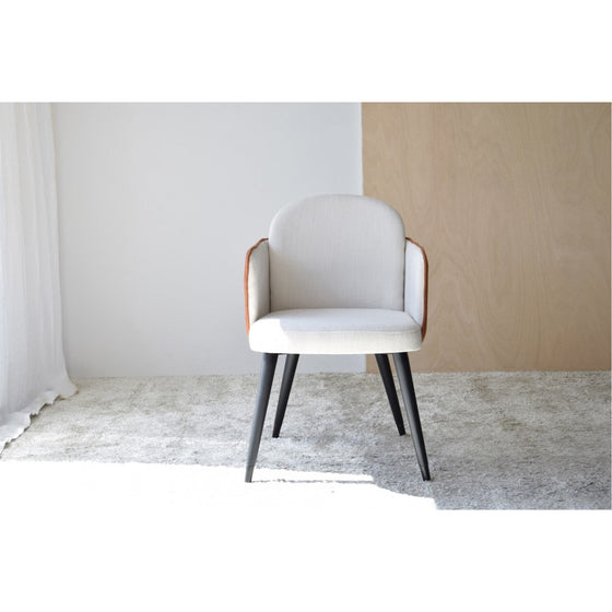 Un Pack 2 Sillas Comedor con Reposabrazos Terrazo se asienta sobre una alfombra gris claro en una habitación minimalista con una pared blanca y un panel de madera.