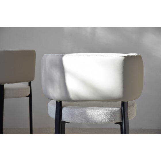 Dos sillas modernas, de colores claros, con respaldo y asiento acolchados, colocadas sobre un suelo de color claro. La luz del sol proyecta sombras sutiles sobre las sillas, realzando su diseño moderno. Este Pack 2 Sillas de Comedor Bern complementa perfectamente cualquier decoración de vanguardia.