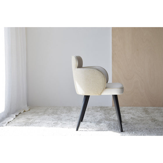 Un Pack de 2 Sillas de Comedor con Brazos Oslo en Beige Natural con patas negras se alza sobre una alfombra de color claro en una habitación minimalista con paredes blancas y de madera, combinando perfectamente funcionalidad y estilo para darle un toque de elegancia Oslo.