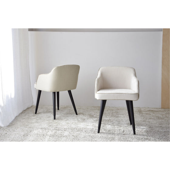 Dos Sillas de Comedor con Reposabrazos Elysare Pack 2 beige con patas negras se colocan sobre una alfombra de color claro en una habitación luminosa con paredes neutras, aportando un toque de diseño cómodo.