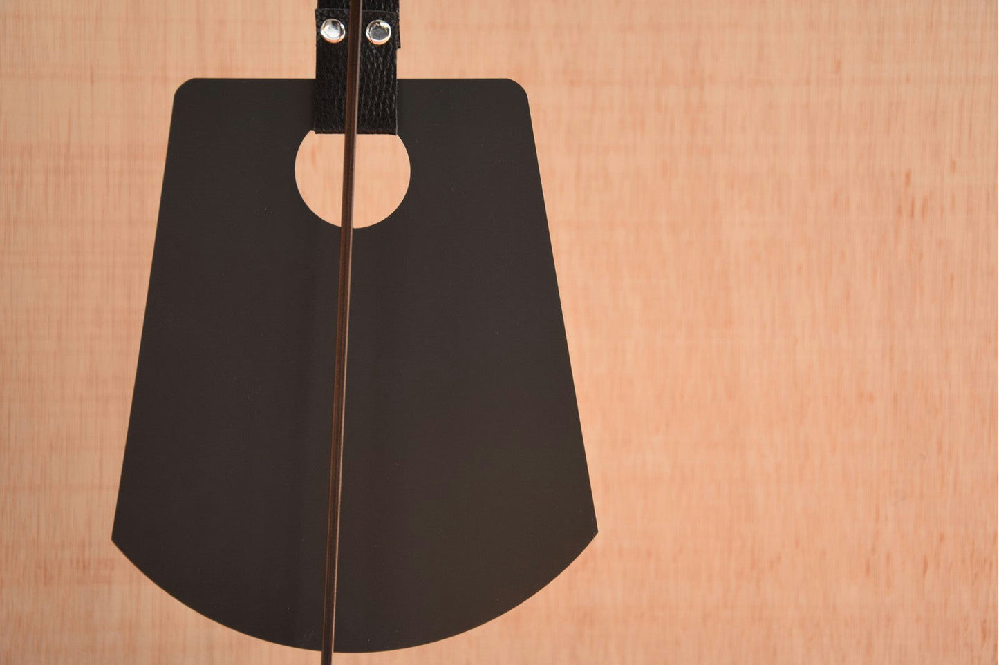 Primer plano de la parte trasera de una guitarra acústica negra, resaltando la parte superior con cuerdas y una textura de veta de madera que recuerda a la Pieza Decorativa Etnica Acero-Mármol N1.