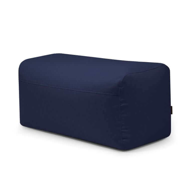 La PLUS 100 NORDIC es una moderna otomana rectangular de color azul oscuro (100×60×45 cm) con bordes redondeados, tapizada en suave tela lavable y rellena de bolitas de poliestireno, ideal como asiento extra en cualquier dormitorio o salón.