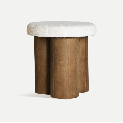 El Puff reposapiés redondo de madera y tela Hoek es un taburete con tablero acolchado en color blanco y base de cuatro cilindros verticales de madera, aportando comodidad y elegancia como asiento adicional ideal para cualquier estancia.