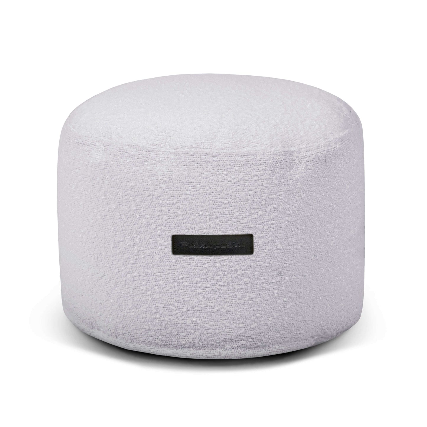 El Puff redondo de tela bouclé MINI MADU (40×40×30 cm) ofrece un asiento cómodo y compacto para dormitorio o salón; destaca su tono gris claro y etiqueta frontal, colocado contra un fondo blanco.