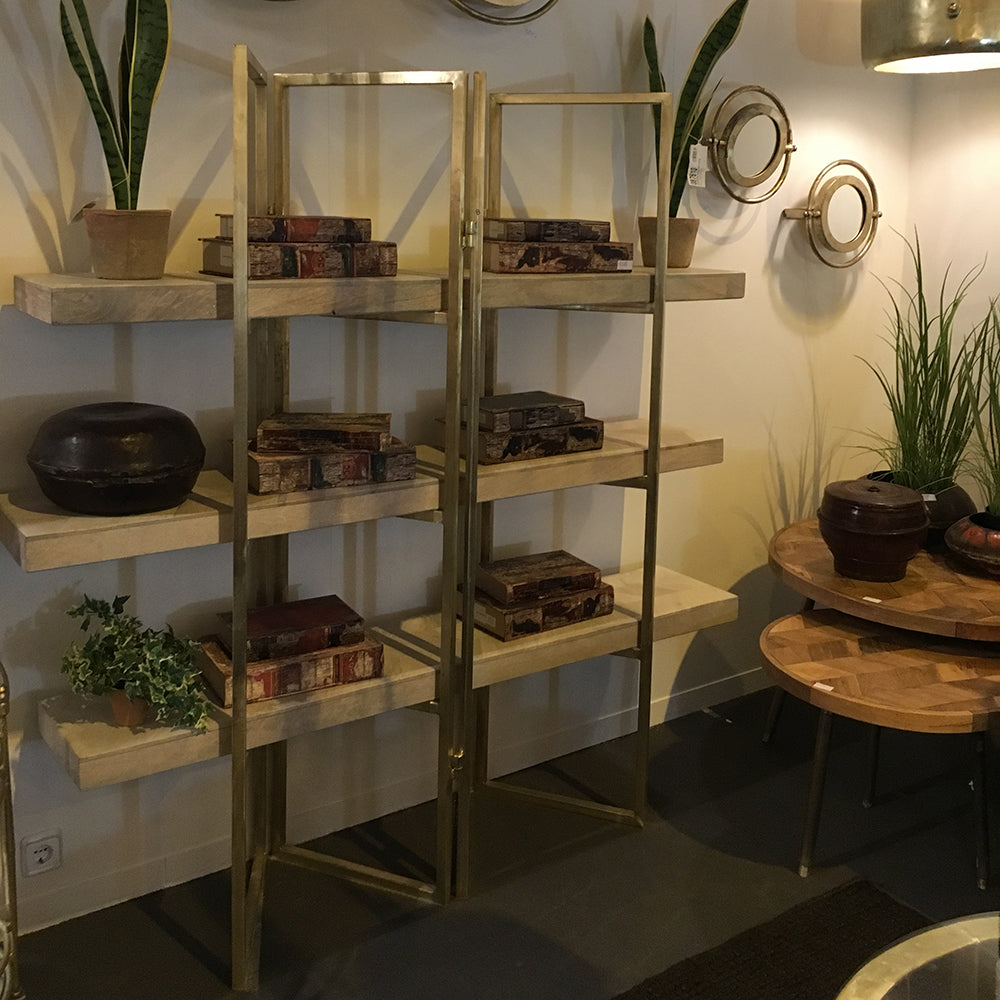 La Estantería Moderna de Hierro y Madera SPACE, decorada con libros apilados, plantas en macetas y cuencos decorativos, se coloca junto a una pared con espejos redondos en una sala de estar de diseño moderno.