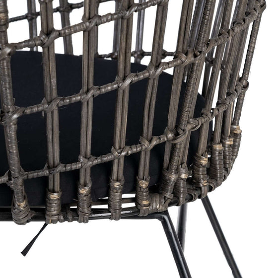 Silla Graphite-Ratan en Gris-Negro moderna con marco de metal negro y detalle intrincado en el respaldo tejido de ratán de alta calidad sobre un fondo blanco.