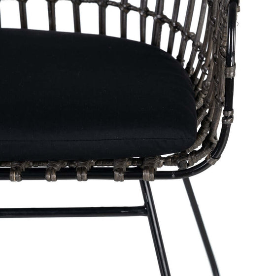 Primer plano de un cojín negro sobre una silla Silla Graphite-Ratan en Gris-Negro con patas de metal.