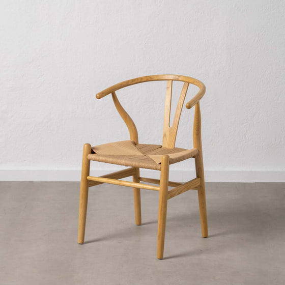 Una Silla Scandbone Marrón en Madera de Abedul con asiento tejido contra una pared blanca sobre un suelo gris.