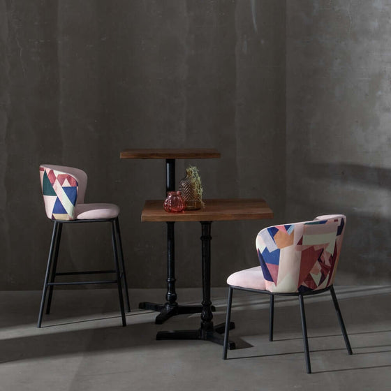 Silla de comedor Abstracto Rosa Palo con estampado geométrico en un entorno minimalista con una mesa de estilo industrial.