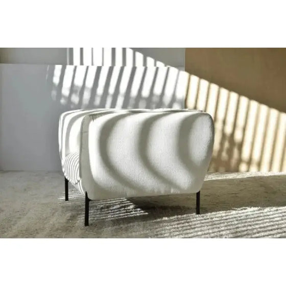 Un Sillón Contemporáneo Formas Curvas en Blanco, colocado frente a una ventana en una habitación.