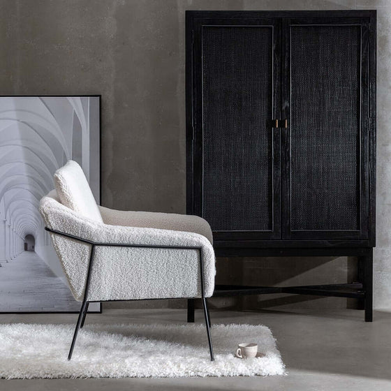 Espacio de vida moderno y minimalista con un Sillón CozyChic en Crudo, una alfombra mullida, un armario y un cuadro enmarcado.