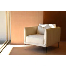  Un sillón cuadrado en lino beige en una habitación.