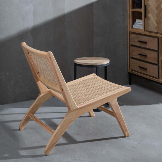 Sillón Natural-Ratán con asiento tejido en una habitación de diseño contemporáneo con un taburete lateral y gabinete.