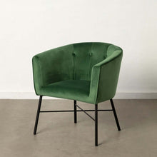  Un sillón Velvetique Terciopelo Verde con respaldo curvado y patas de metal negro en contraste con un fondo neutro.