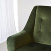 Un Sillón de Diseño en Terciopelo Verde "Oscuro" complementa elegantemente un telón de fondo blanco, encarnando la esencia del interiorismo moderno.