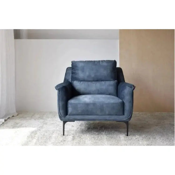 Un Sillón de Terciopelo Azul Desgastado - Elegancia Urbana contemporáneo, colocado frente a una pared blanca y limpia.