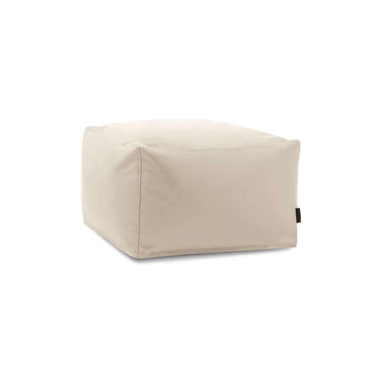 El Pouf Softbox Colorin - uso exteriores es un puf cuadrado de tela beige con costuras visibles y una pequeña etiqueta lateral negra, que se muestra sobre un fondo blanco.