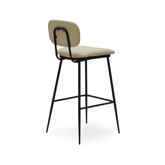 El "Taburete Alto en Metal y Tapizado Cushi" es un taburete de bar moderno con asiento y respaldo acolchados en color beige. Cuenta con un diseño ergonómico sostenido por una estructura de metal negro con reposapiés.