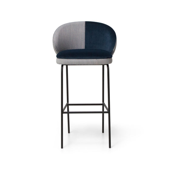 El Taburete Alto en Metal y Tapizado Koko presenta un asiento y respaldo tapizados en azul oscuro y gris, sostenido por una estructura de metal negro con reposapiés, mostrando diseño contemporáneo.