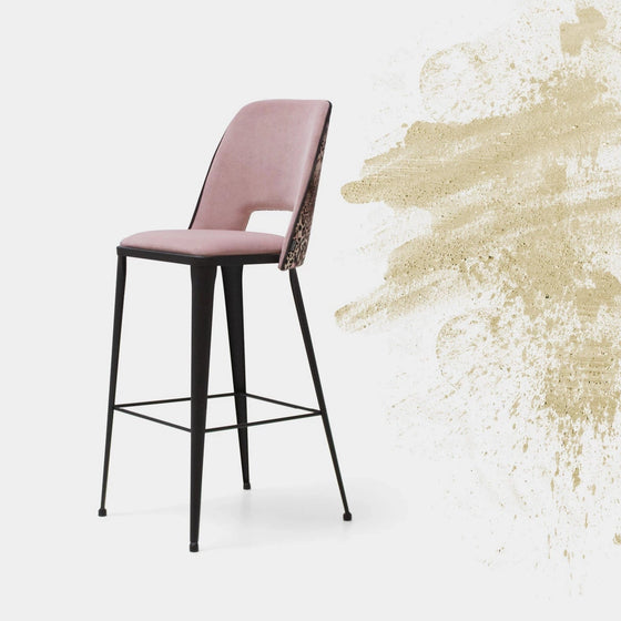 Sobre un fondo blanco con un diseño de salpicaduras de pintura beige en el lado derecho, el Taburete Alto en Metal y Tapizado Paulina Industrial destaca por su asiento y respaldo acolchados en rosa, sostenidos por delgadas patas negras. Su diseño industrial se ve realzado por opciones tapizadas personalizables para darle más estilo.