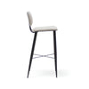 Vista lateral del Taburete Alto en Metal y Tapizado Umai que presenta un asiento y respaldo acolchados en color blanco, sostenido por una elegante estructura de metal negro con patas y reposapiés, mostrando su sofisticado diseño.