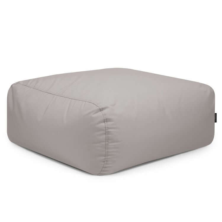 El Puf cuadrado TUBE 80 COLORIN (85×85×38 cm) ofrece diseño moderno y tejido resistente al sol, ideal para interior y exterior. Suave superficie gris claro y bordes redondeados, perfecto como asiento exterior, sobre fondo blanco.