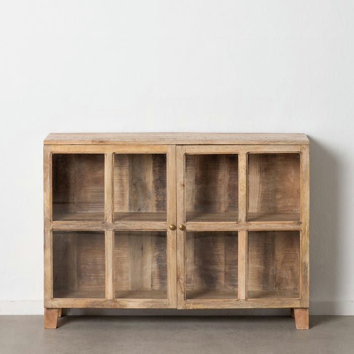 La Vitrina Baja Natural Blanco Rozado en Madera de Mango, con cuatro puertas con paneles de vidrio y perillas de metal, se destaca elegantemente contra una pared blanca lisa sobre un piso gris, incorporando un exquisito diseño de interiores.