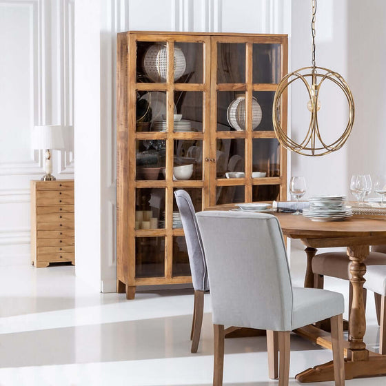 Elegante comedor con mesa de madera con sillas, vitrina Vitrina Natural y lámpara de araña moderna.