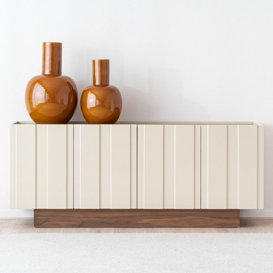 El aparador de DM lacado beige brillo OBI (198×48×80 cm) con sobre y base de nogal aporta almacenamiento y realza el diseño contemporáneo de tu hogar, ideal para destacar junto a jarrones cerámicos marrón.