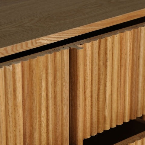 Un primer plano del Aparador Skagen, con sus ranuras verticales y su superficie lisa, elaborado a partir de refinada madera DM y paulownia para un diseño minimalista moderno.