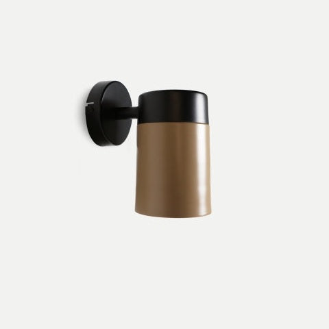 Realza tu espacio con el aplique de pared en hierro negro y dorado Aston, una lámpara cilíndrica marrón con base negra, que encarna el diseño art déco. Ideal para iluminación decorativa, resalta sobre un fondo gris claro.