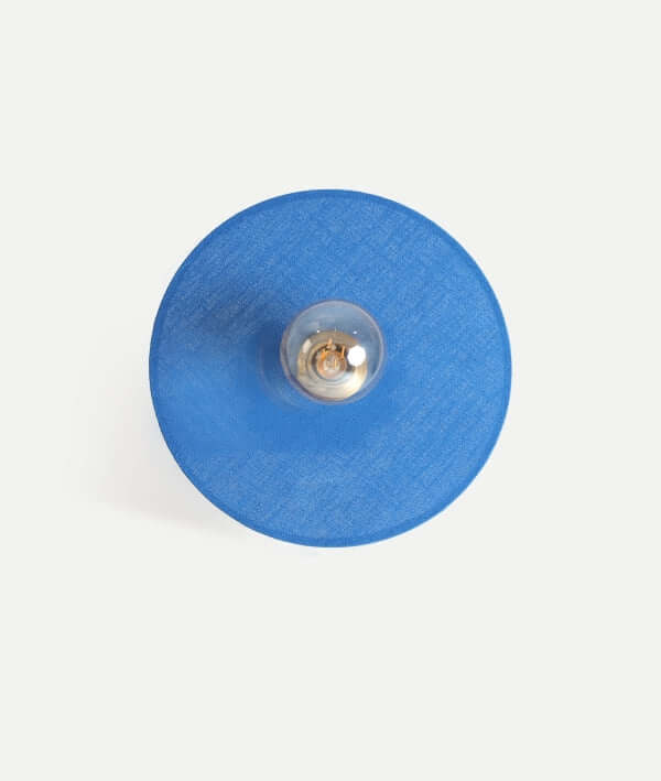 Vista aérea del aplique de pared VETRA de algodón azul y metal dorado (33×9×33 cm), con una bombilla expuesta en el centro, un toque de iluminación decorativa elegante y contemporánea.