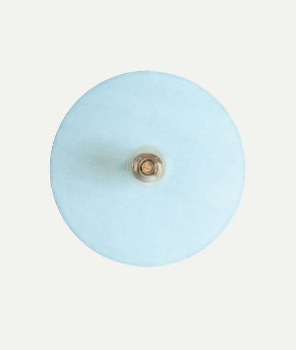 Un aplique de pared KODU VETRA, de algodón celeste y metal dorado (45×9×45 cm), se destaca sobre fondo blanco. Ideal para añadir iluminación ambiental y complementar un diseño contemporáneo.